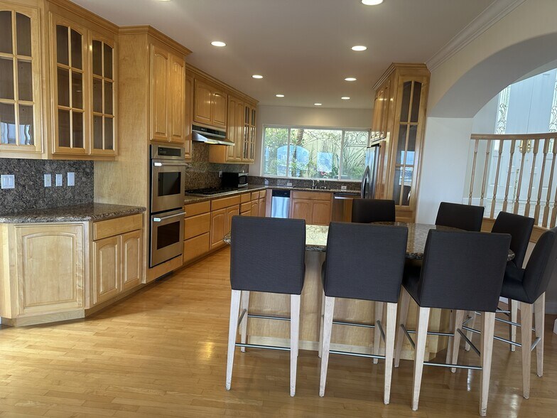Spacious chef’s kitchen with granite island seating for seven, glass-paneled cabinetry, double ovens - 8120 Billowvista Dr