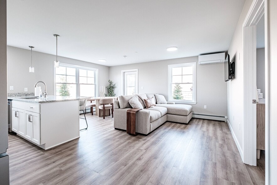Enjoy bright, open-concept living with a seamless flow between the kitchen, dining, and living areas, enhanced by abundant natural light and modern finishes. - Windham Village Apartments