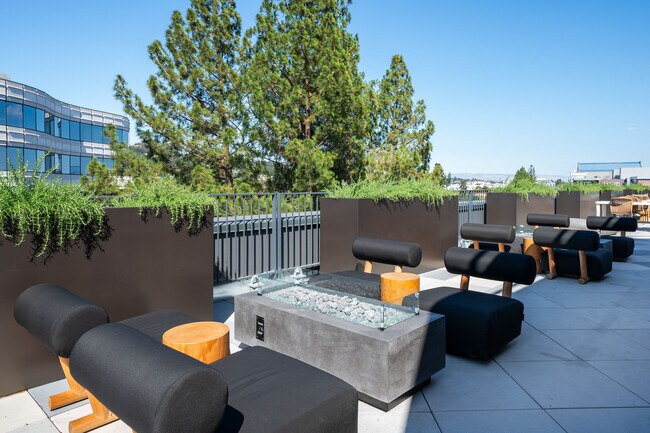 Elegant rooftop lounge with modern furniture and greenery overlooking the city. - Akin Residences