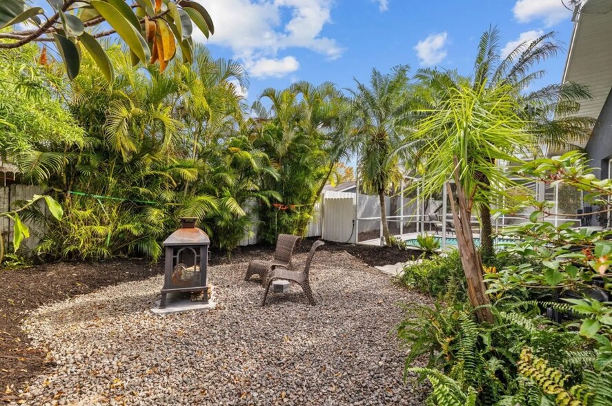 Tropical backyard retreat with cozy fire pit and seating area. - 1932 Brainerd Ct