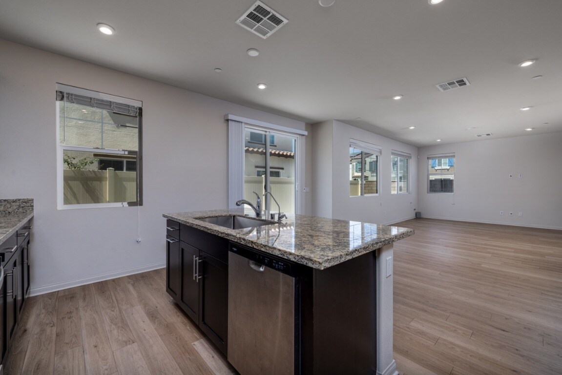 Open-concept kitchen with laminate flooring, island granite countertop - 26549 Brightstone Dr