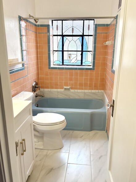 Original tile and stained glass window in bathroom. New floor, toilet and vanity - 5070 Oleatha Ave