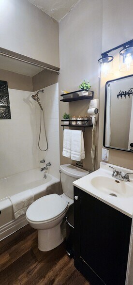 Modern vanity with bright lighting, plush hand towels, and wall-mounted hair dryer. - 822 E 4th St
