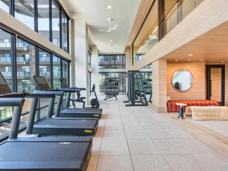 Light-filled fitness center with premium cardio and strength equipment plus relaxing lounge seating nearby. - Modera Reserve