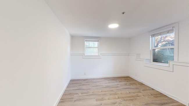 Spacious room with wood-like flooring and a large window offering natural light - 2333 Channing Way