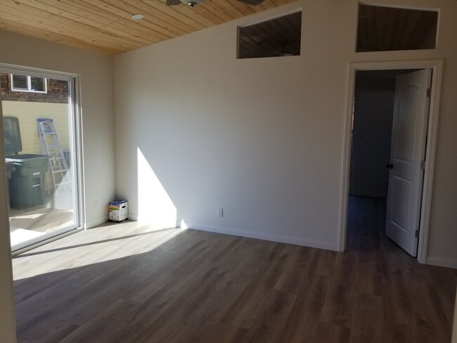 Living room with high wood ceilings, ceiling fan and sliding door to outdoor patio - 6832 Zelzah Ave