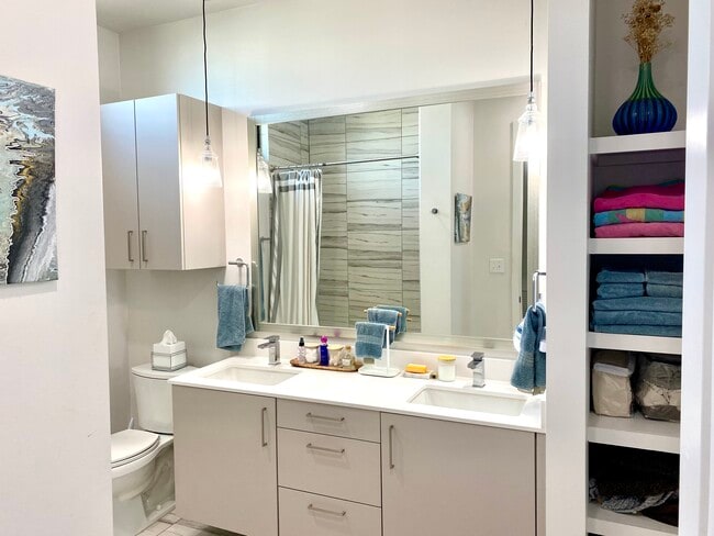 Dual-vanity bathroom with plenty of cabinet storage and stocked linens. - 1501 E 4th St