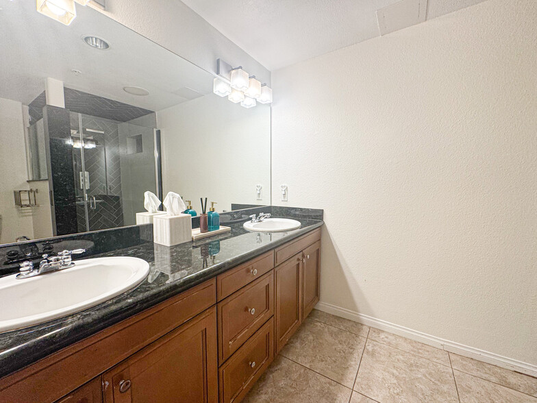 Modern primary bathroom with granite counters, double sinks, and plenty of storage - 3740 Santa Rosalia Dr