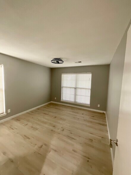The master bedroom featuring large windows, walk-in closet, LED ceiling fan, and hardwood flooring - 12743 W 110th Ter