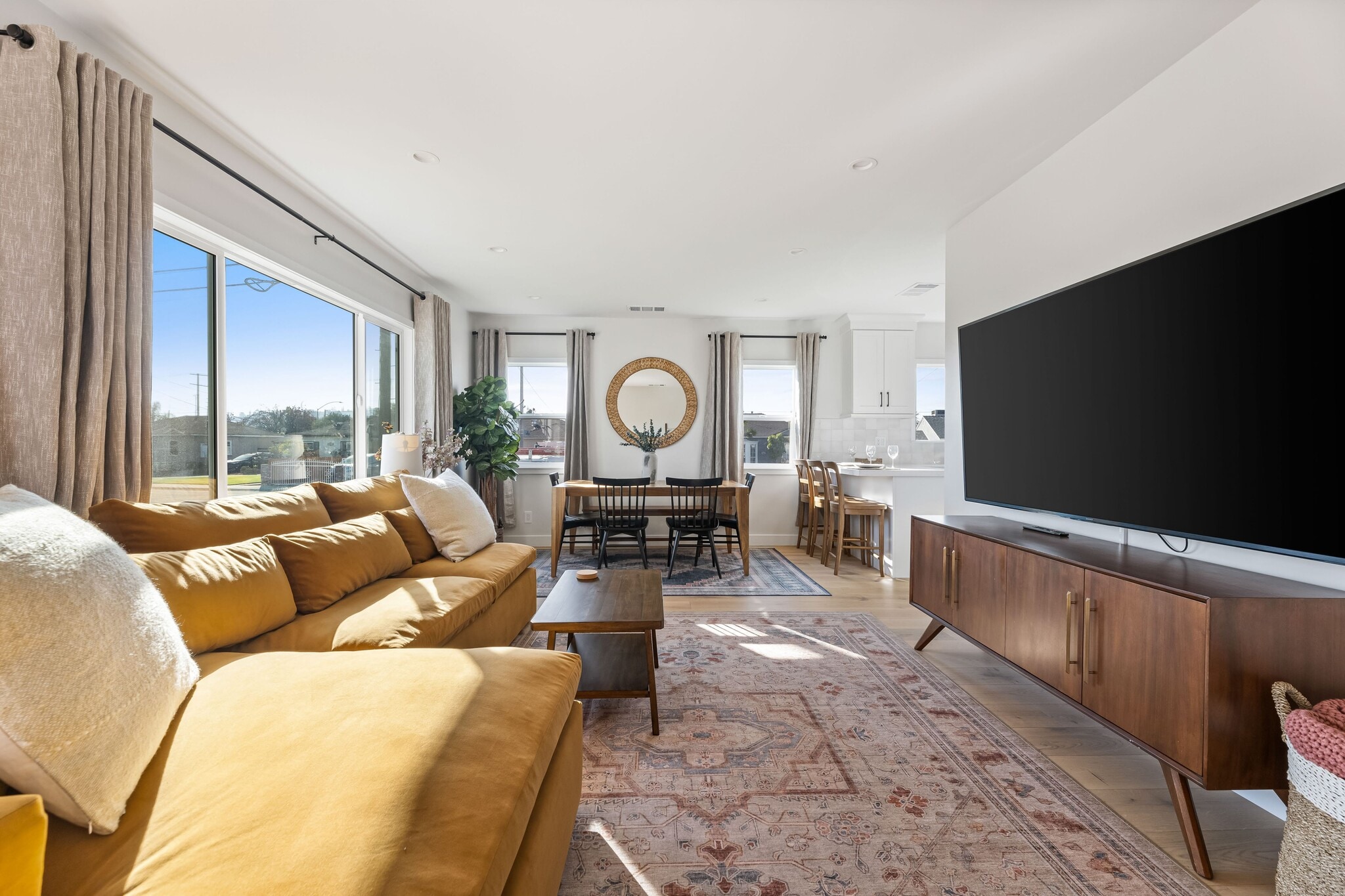 Living room with West Elm furniture, natural sunlight, and large TV flatscreen. - 1823 N Ditman Ave