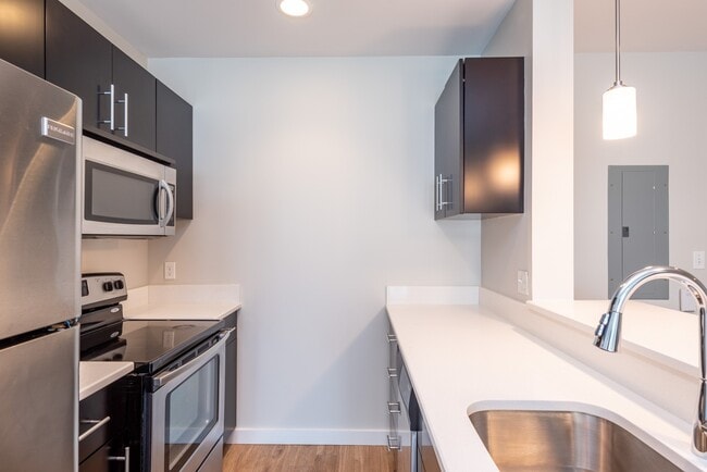 Please note that the countertops may vary by unit. While some feature lighter granite with a beige and brown pattern, others have a more white finish. - Renaissance Station North