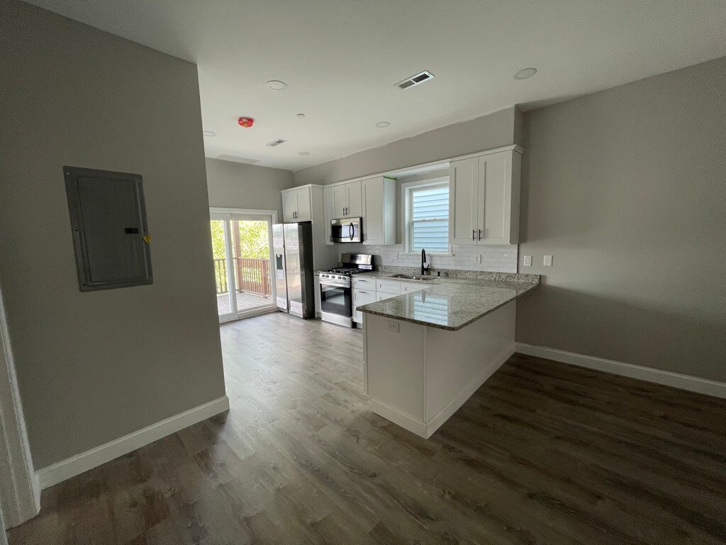 Unit two: view of open-concept kitchen and patio with bedroom two to the left. - 34 Falcon St