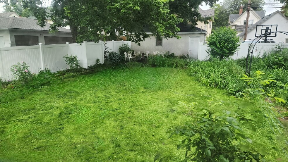 Spacious fenced backyard with mature trees, garden beds, a natural lawn, and room to relax or play. - 1901 -2301 Fillmore Street NE Minneapolis, MN 55418