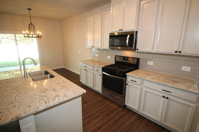 Kitchen features large island, granite counters, tile backsplash, 42 inch cabinets, gas range & upsc - 3406 Dropseed Dr
