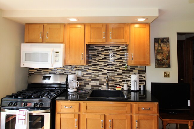 Kitchen with tiled backsplash, gas range and microwave - 2820 NY-28