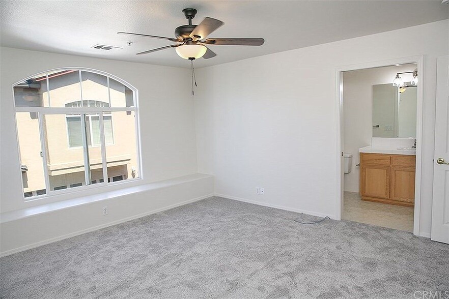 Primary bedroom with full length of wall window seat, large arched window and ensuite bathroom - 3051 Augusta St