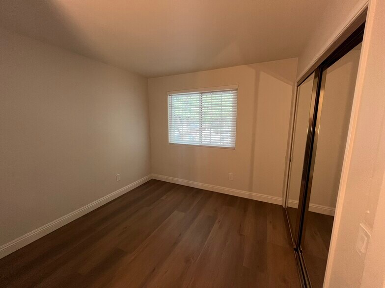 Bedroom with mirrored closet doors with LVP and baseboards in closet. - 16274 Avenida Venusto