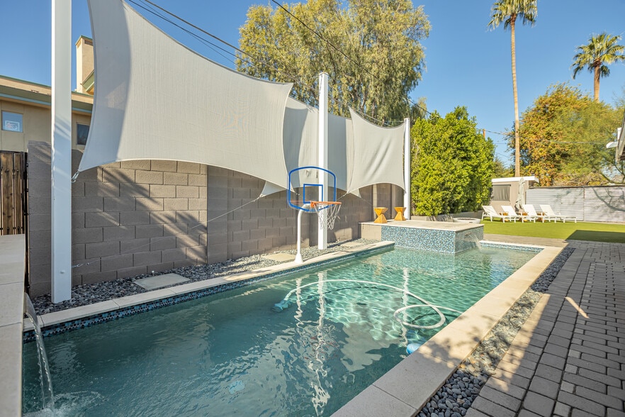 Private swimming pool with dual waterfalls, sun deck, and custom privacy structures - 6136 N 9th St