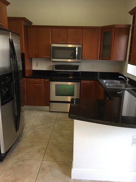 Kitchen with stainless steel appliances and black granite. - 17802 NW 74th Ct