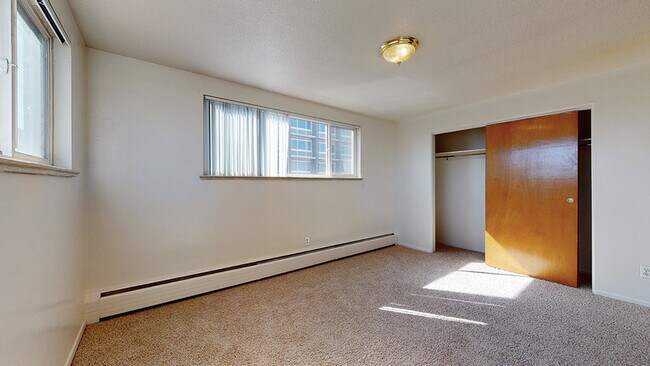 Experience the warmth and comfort of this sunlit bedroom, complete with a roomy closet. - Harmony Apartments