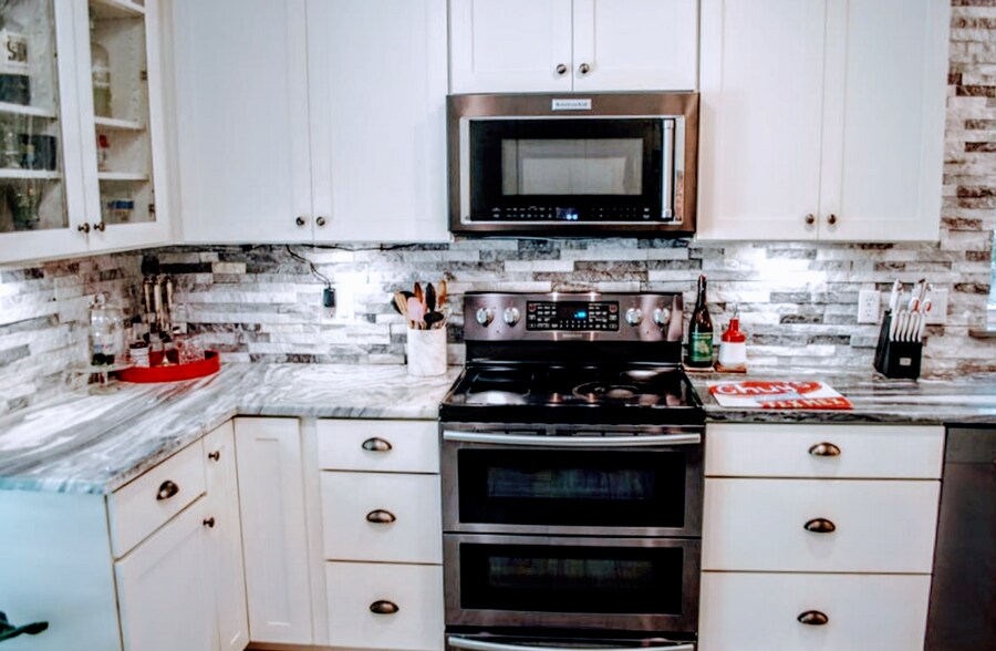 Slate-color appliances, natural stone counters and backsplash with under-cabinet lighting - 2 Arnica Ct