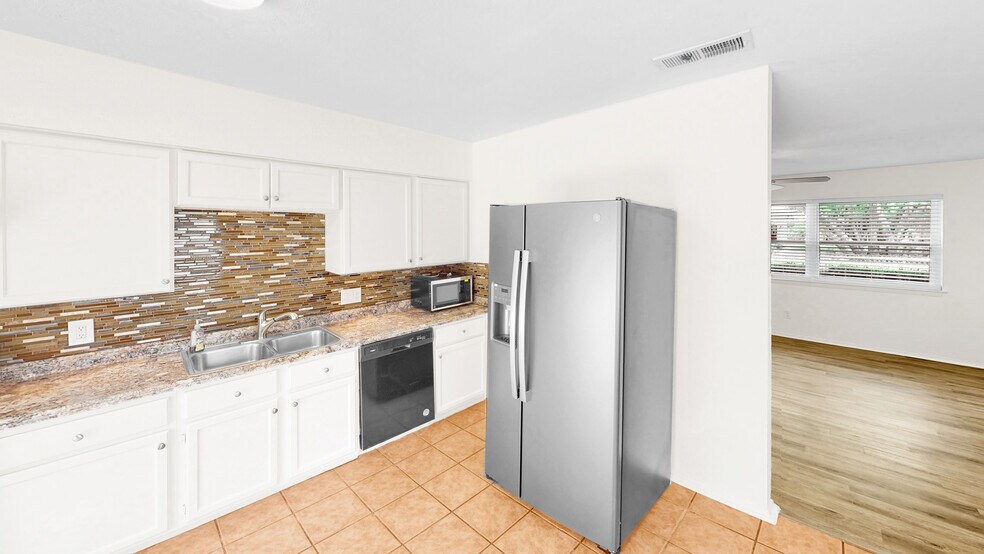 Kitchen with stainless steel appliances, a sink, white cabinets, and decorative backsplash - 5906 Wagon Bnd