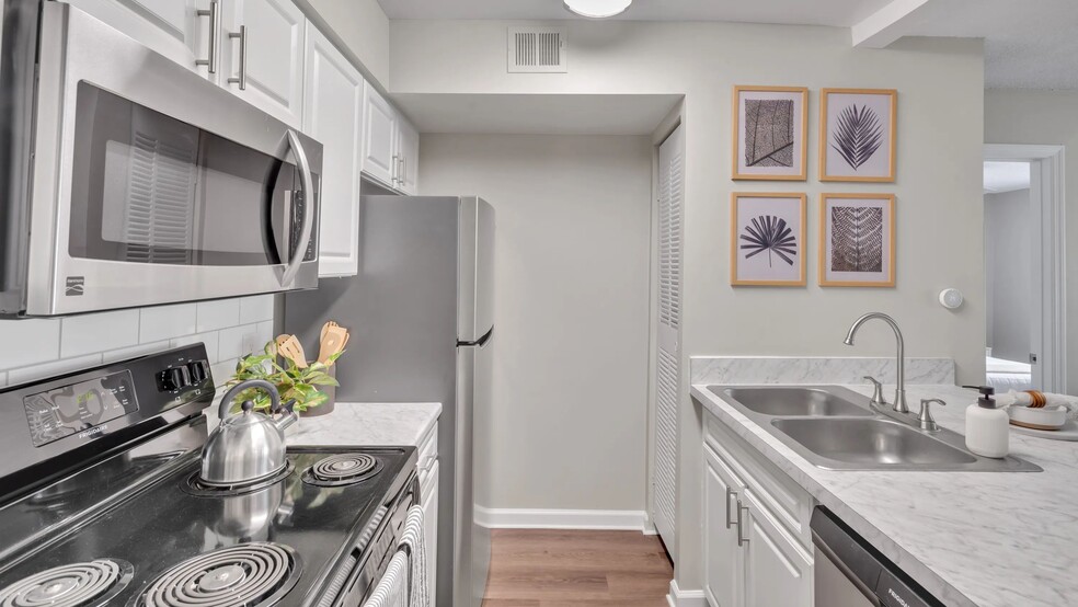 Our floor plans showcase galley-style kitchens with modern, pristine white cabinetry and stainless-steel appliances, creating a kitchen of grace and practicality. - River Bluff of Lexington