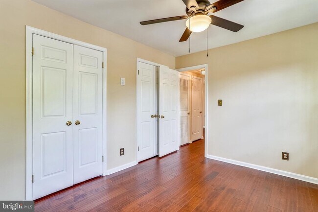 Primary bedroom with two full closets and ceiling fan. - 1415 E Abingdon Dr