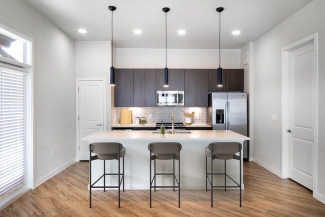 Kitchens with stainless steel appliances, wine fridges, quartz countertops, tile backsplash, and hard surface flooring - Avalon Townhome Collection Bee Cave