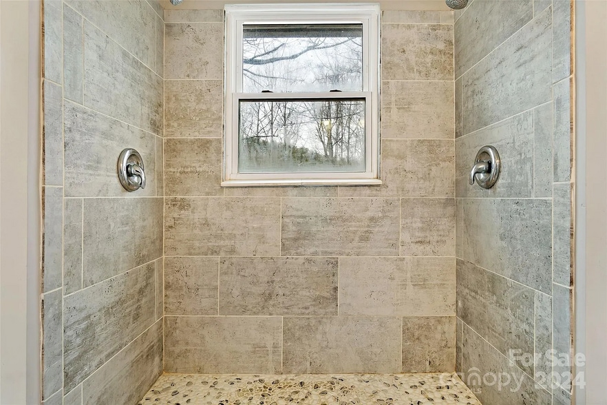 Stone shower with pebble floor and dual shower heads. - 228 Barrett Rd