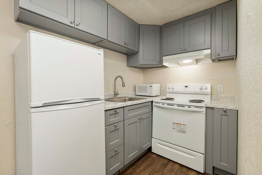 Kitchen with oven, stove, microwave & refrigerator - Badger Apartments