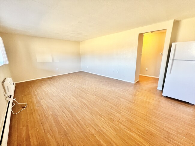 Experience openness in this spacious living room featuring elegant hardwood flooring. - 1690 Eaton