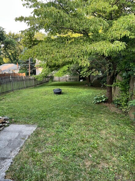 A view of the fenced in backyard, which features two Dogwood trees and a plastic shed. - 126 Merion Ave