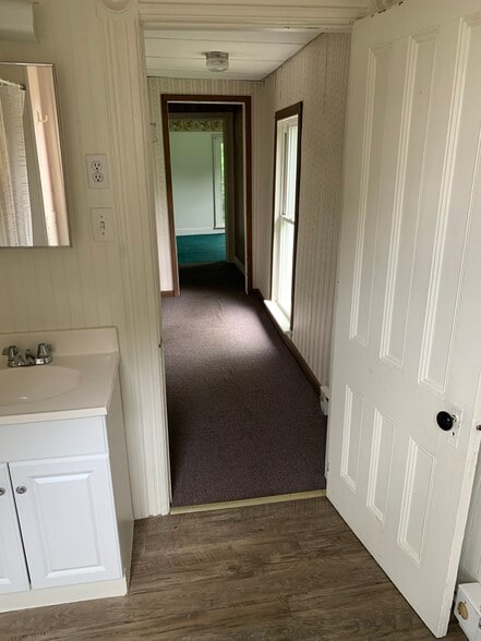 Bathroom looking into hall way towards kitchen to left and bedroom1 at the end - 7614 Collins St