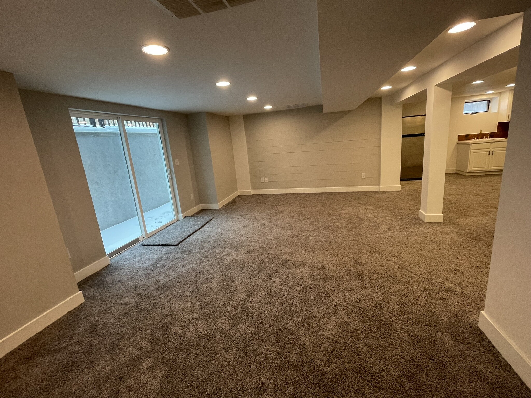 Basement primary bedroom with sliding door to private patio and cool shiplap wall - 508 Daly Ave