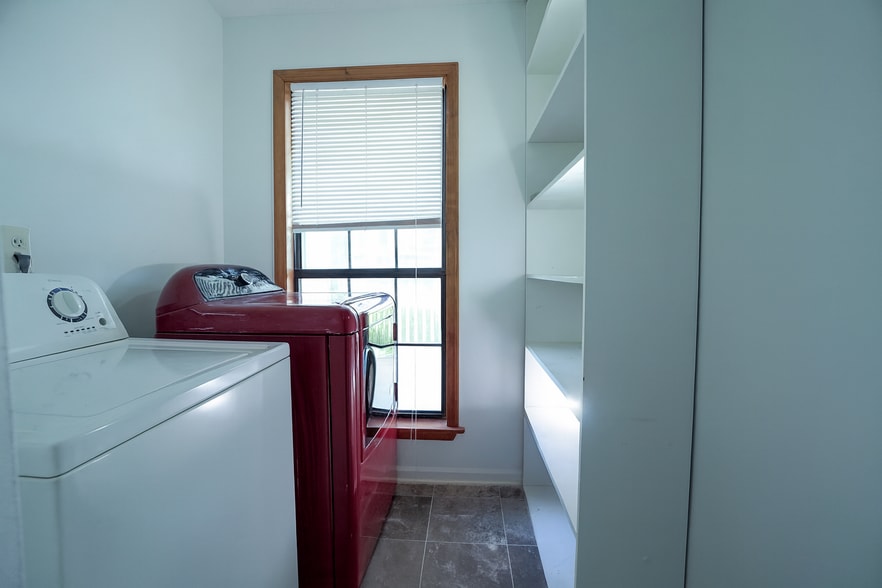 Bright laundry room with shelving, tiled floors, and natural light for a clean, airy feel. - 2313 Salem West Dr