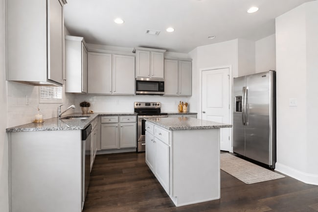Spacious kitchen with an island, ample storage, stainless steel appliances and view into the living room. - Chase Landing