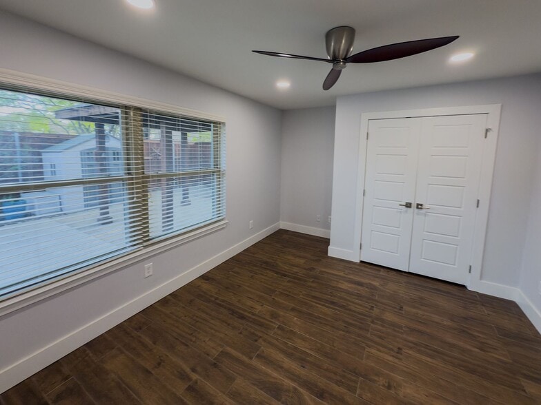 Bedroom with modern ceiling fan, window, and double closet doors - 2006 Candle Ct