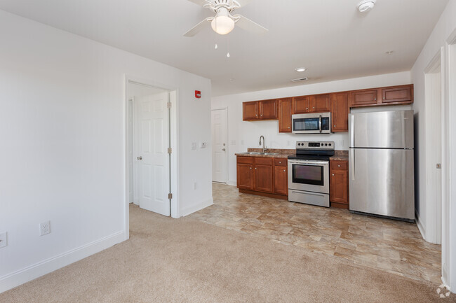 Carpeted living room towards kitchen. - Hemingway Apartments