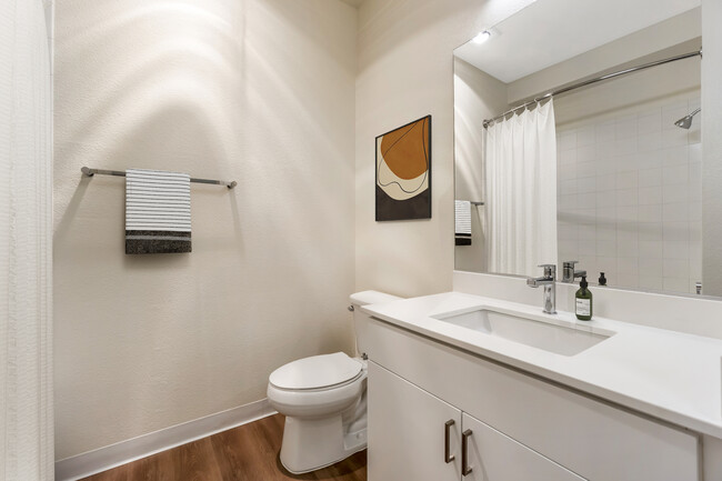 Renovated Package I bath with white quartz countertop, white cabinetry, and hard surface flooring - Avalon ParcSquare