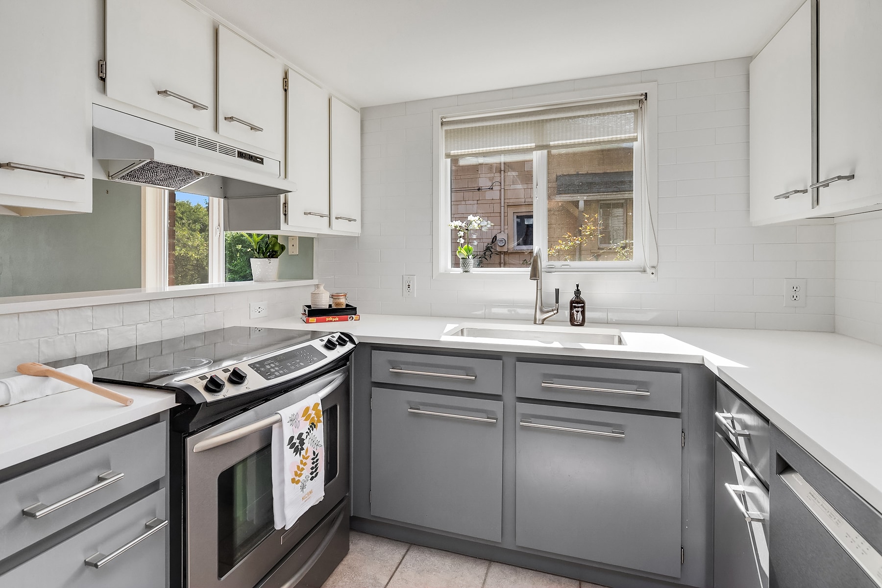 Kitchen updates include new tile walls from counter to ceiling and backsplash detail behind kitchen bar. Crisp white quartz counters with new drop-in sink and faucet, slide in range, brand new KitchenAid dishwasher & Liebherr refrigerator. - 7051 8th Ave NW