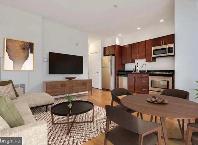 The spacious living area can easily fit a dining set, a couch, coffee table, TV, and storage. - 2910 Georgia Ave NW