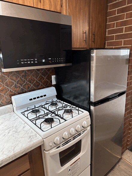 Kitchenette with fridge, four burners gas stove and microwave with exhaust hood. - 834 S Walnut St