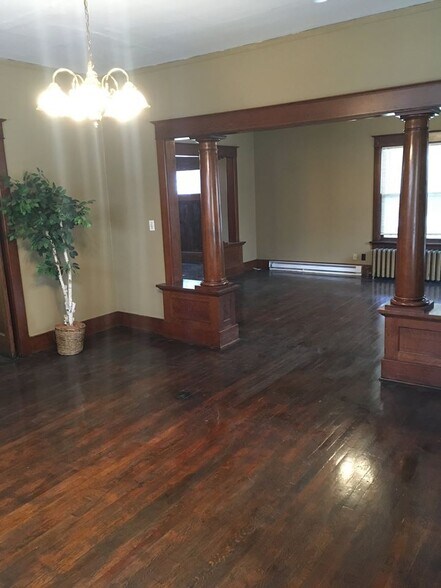 Newly refinished hardwood floors, dining room looking into living room, separated by stately wooden columns - 1545 S 13th St