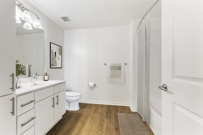 Renovated Package I bath with white laminate countertops, white cabinetry, and hard surface flooring - Avalon at Wesmont Station