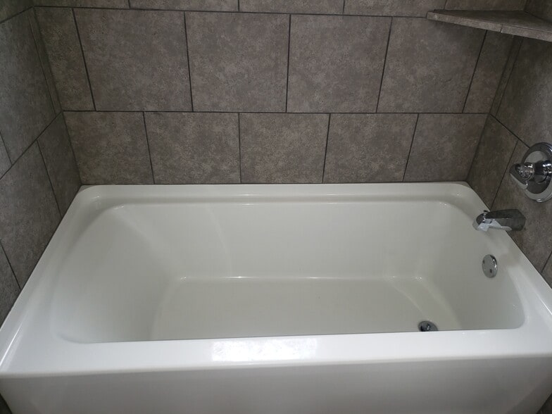 Large soaking tub surrounded in gray tile and frosted window for natural lightning - 2713 Jenkins St