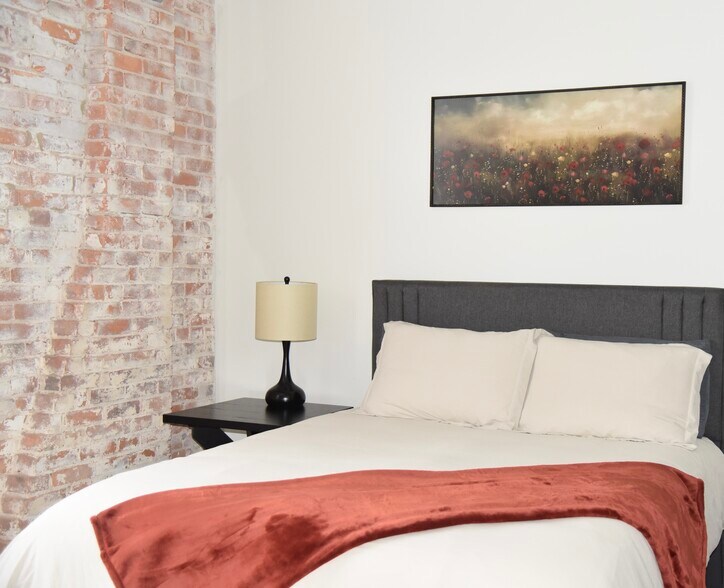 Primary bedroom features a queen size bed, a Smart TV, walk-in closet and en-suite bathroom. - 101 W Broadway St