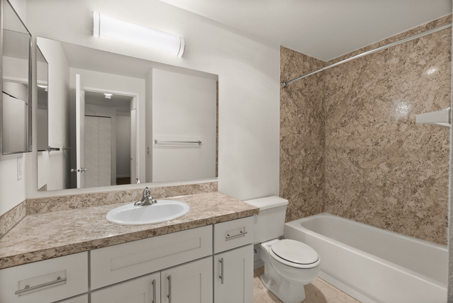 Modern bathroom with elegant marble walls, sleek vanity, and bright lighting, offering a luxurious and functional space. - Windemere Apartments