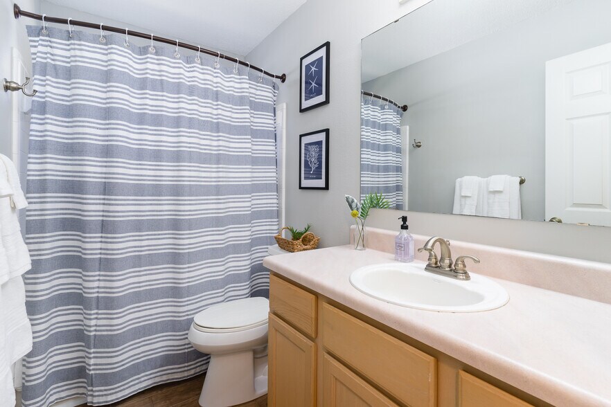 The shower with a hotel-style curved curtain holder and toiletries. - 6464 Starfish Cv