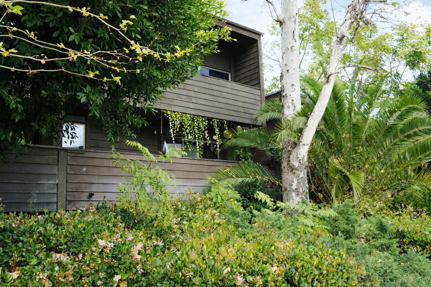 Lush greenery surrounding the building creating a calm residential setting. - 4401 Kraft Ave